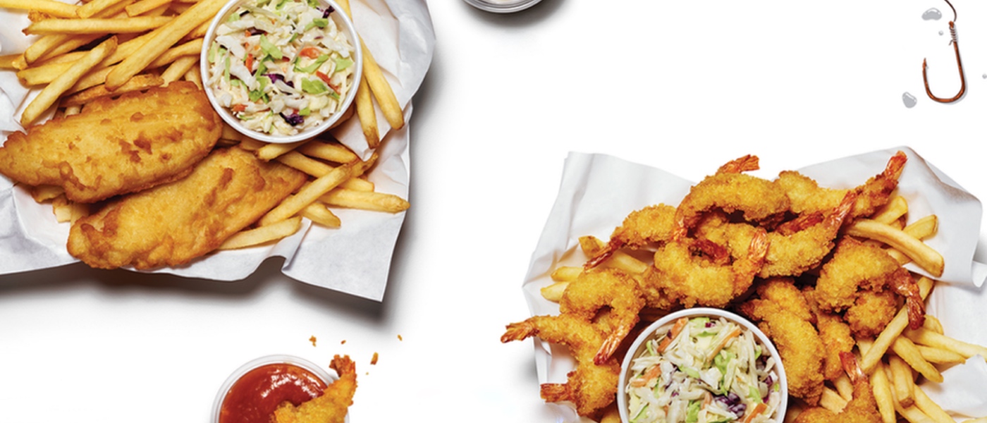 Overheard shot of two pub style baskets. One with cod, the other with shrimp. Both have fries and coleslaw.